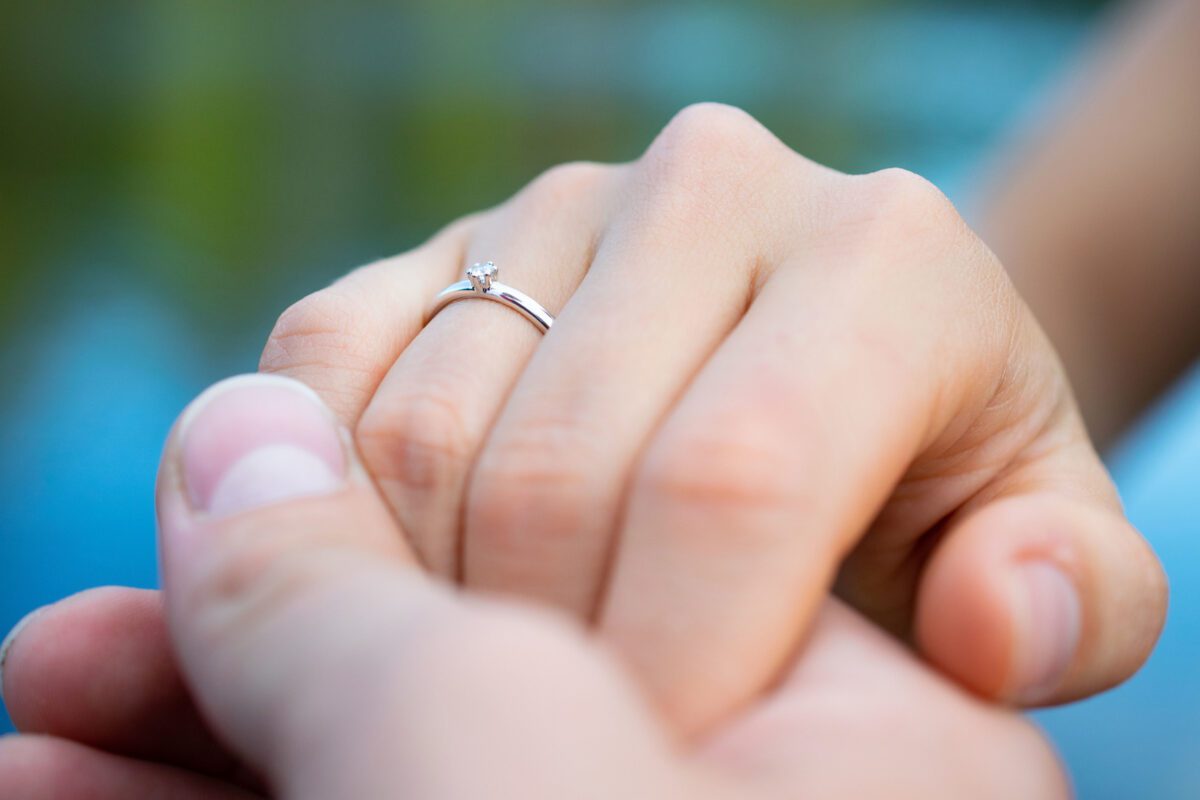 Closeup shot of the hands of a couple with an engagement ring – love concept
